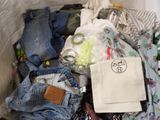a basket full of clothes and other items on a bed