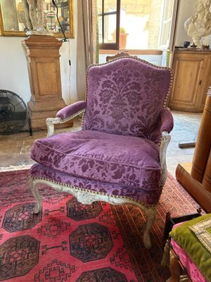 a purple chair sitting in a living room with a rug on the floor