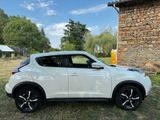 a white nissan juke parked in front of a stone building
