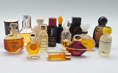 de nombreux flacons de parfum de styles variés posés sur une surface blanche