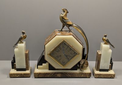 une horloge surmontée d'un oiseau, à côté de deux bougies