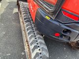 a red tractor with a black tire on the street