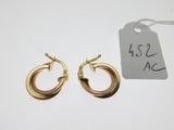 two pairs of gold hoop earrings on a white surface with a price tag