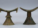 paire de cornes d'éléphant en laiton ancien posées sur des socles, sur fond blanc