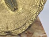 a gold plate with a bird on it on a marble base