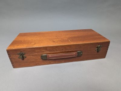 une vieille boîte en bois munie d'une poignée en cuir, posée sur une table
