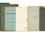 several old books sitting on top of each other on a white surface