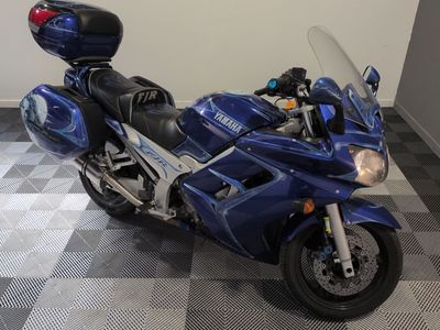 une moto bleue garée sur un sol à damier