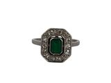 gros plan d'une bague avec une pierre verte entourée de diamants blancs
