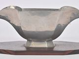 a silver vase sitting on top of a wooden stand