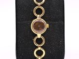 a close up of a gold bracelet with a brown stone on it