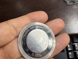 someone is holding a silver coin in their hand near a keyboard