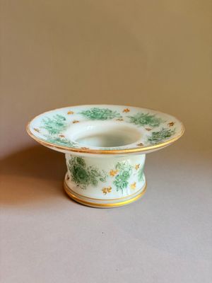 un bol vert et blanc à bord doré posé sur une table