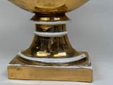 a gold vase with a white base on a white background