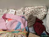 a pile of clothes and a purse sitting on a bed