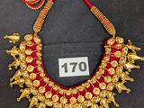 une photo d'un collier en or orné de perles rouges et dorées