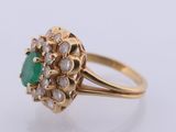 a close up of a gold ring with a green stone surrounded by white diamonds