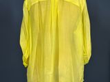 a yellow shirt on a mannequin stand against a blue wall