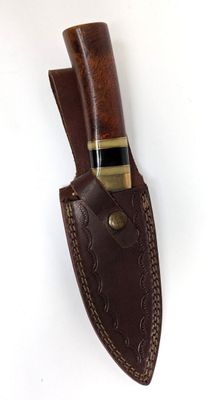 un étui en cuir marron sur lequel repose un couteau, posé sur une surface blanche