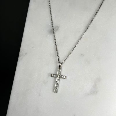 a close up of a cross on a necklace on a marble surface