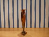 un vase marron posé sur une table en bois devant un mur rayé