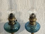 deux lampes en verre bleu posées l'une à côté de l'autre sur une table