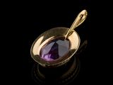 a close up of a gold plated pendant with a purple stone