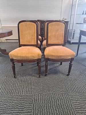 three chairs with upholstered back cushions in a room with a table and chairs