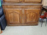 a wooden cabinet with two doors and a red chair in front of it