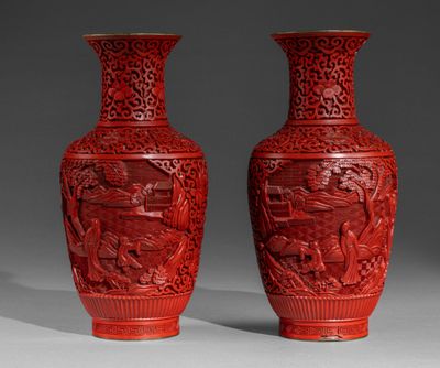 une paire de vases rouges ornés de motifs sculptés sur un fond gris