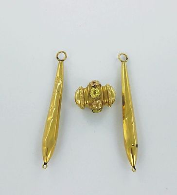 pair of gold plated earrings and a gold bead on a white surface