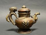 a bronze teapot with a dragon on the lid