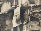 une vieille photo en noir et blanc montrant un drapeau flottant devant un bâtiment