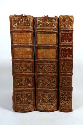 three old books are stacked on top of each other on a white surface