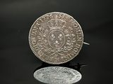 une vieille pièce d'argent posée sur une table, à côté d'un miroir