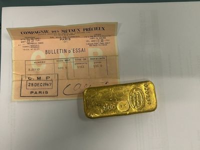 a gold bar next to a receipt on a table