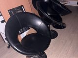 trois fauteuils en cuir noir dans une pièce où une planche de surf est accrochée au mur