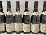 six bouteilles de vin sont alignées sur une table