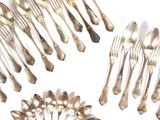 de nombreuses cuillères en argent et des cuillères à soupe posées sur une surface blanche