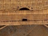 a cat sitting in a wicker chair on a tiled floor