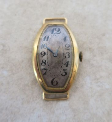 une montre en or posée sur une surface blanche