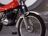 a red motorcycle parked in a parking lot next to a white wall