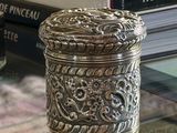 a silver box sitting on a glass table next to a pile of books
