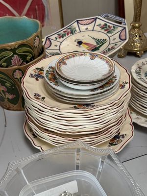several plates and bowls are stacked on a table with a glass container
