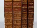 several old books are lined up in a row on a white surface