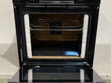 a black oven with a glass door and a wooden shelf