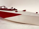 a red and white boat sitting on a white surface