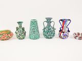 five different colored vases sitting next to each other on a white surface