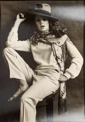 black and white photograph of a woman sitting on a chair wearing a hat