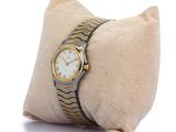 a watch sitting on a pillow on a white surface